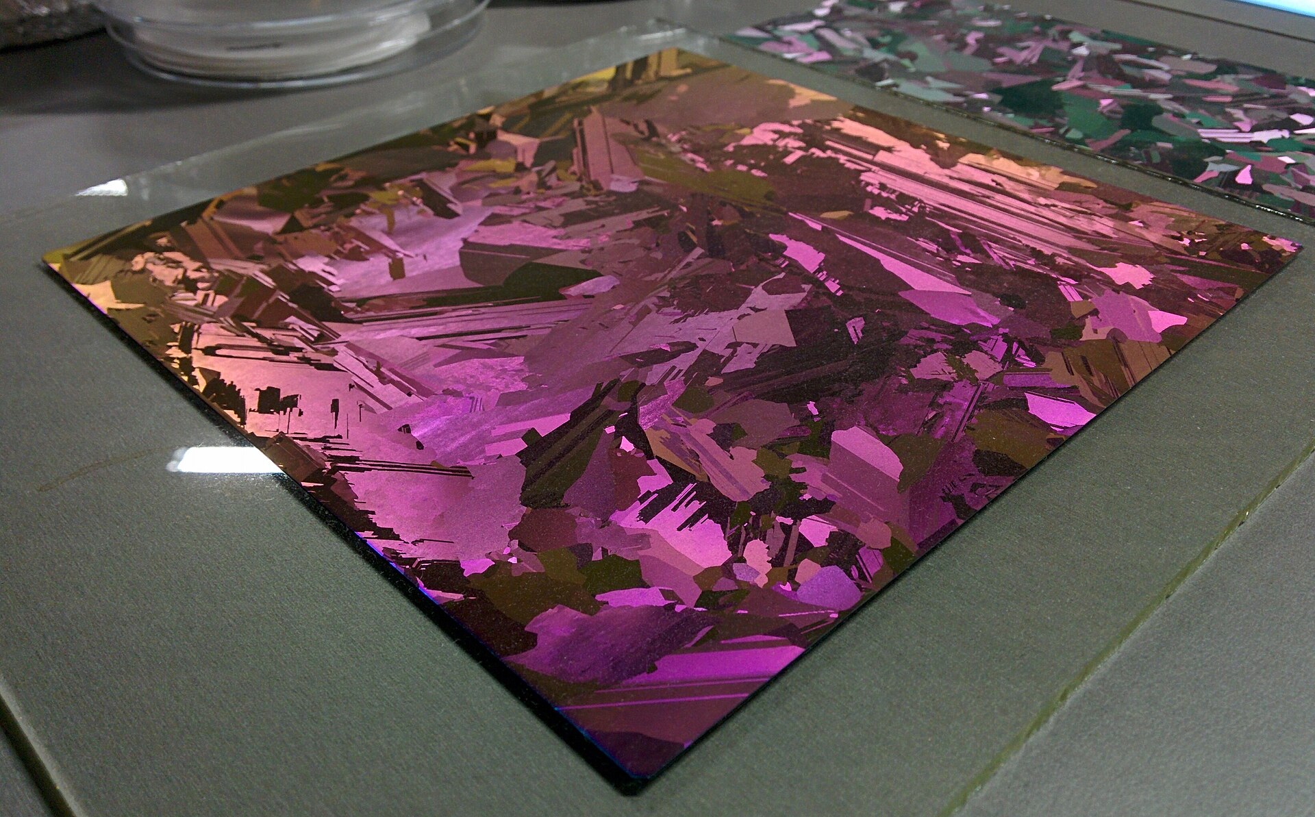 Galette de silicium aux reflets irisés posée sur une plaque de verre